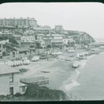 View across Ventnor from the western cliffs looking across the town and beach. There are many bathing huts and boats on the beach