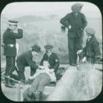 Three ambulancemen carrying out a training exercise with a patient laid out on a concrete floor. Sandown in 1914