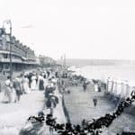 Esplanade and beach at Sandown with beach huts etc. Culver Cliff in the distance