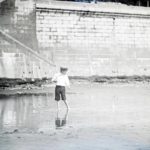 Young boy playing with a toy boat in a pool on the beach