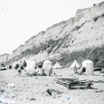 Beach scene at Sandown with people and tents