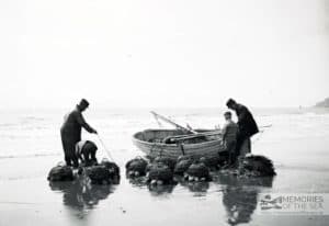 Open boat returning to shore at Ventnor, fishermen unload lobster pots