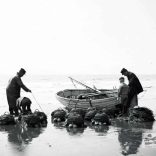 Open boat returning to shore at Ventnor, fishermen unload lobster pots